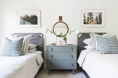 two beds in a room with pictures on the wall above them and a dresser below