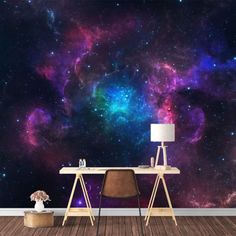 a desk with a lamp on it in front of a wall that has an image of the sky and stars