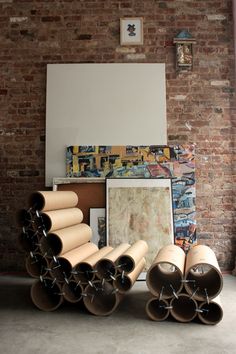 a bunch of pipes sitting in front of a brick wall next to a painting on a easel