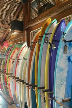 many surfboards are lined up in a row on the wall and hanging from hooks