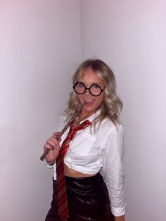 a woman wearing glasses and a tie poses for the camera with her tongue hanging out