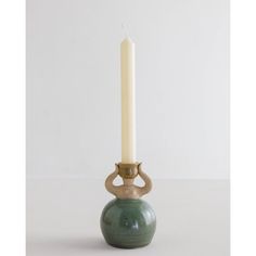 a candle that is sitting on top of a green vase with a white candle in it