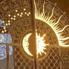 the sun and moon are lit up in front of an iron gate with intricate designs