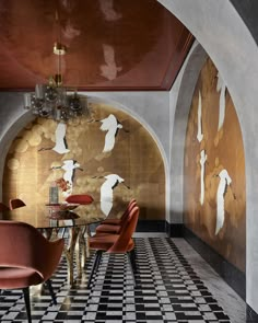 a dining room with black and white checkered flooring, red chairs and wall art