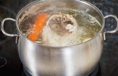 a pot on top of a stove filled with boiling water and an orange carrot in it