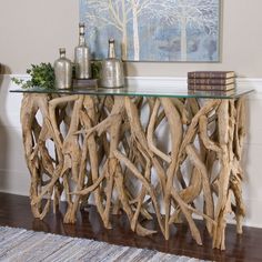 a table made out of driftwood with books on top and vases sitting next to it