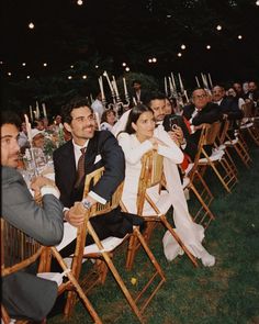 a group of people sitting on top of wooden folding chairs