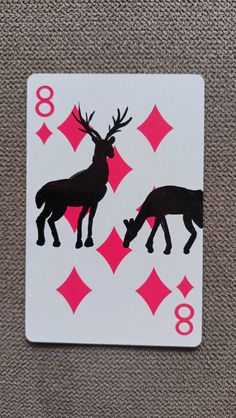 a playing card with two deers on the front and four pink diamonds on the back