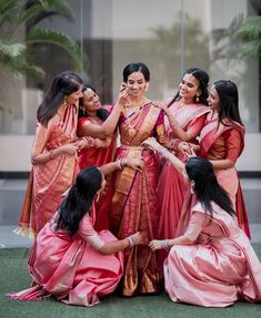 a group of women standing around each other in pink and gold sari attires