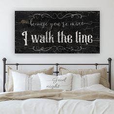 a bed with pillows and a sign above it that says, because you're mine i walk the line