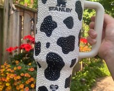 a person holding up a coffee cup decorated with black and white spots