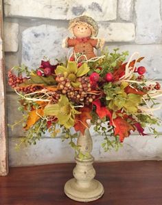 a vase filled with lots of colorful flowers and leaves on top of a wooden table