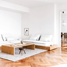 a living room with white couches and wooden tables in the middle of the room