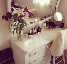 a white dresser topped with a mirror and a vase filled with flowers