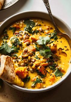 a white bowl filled with food next to bread