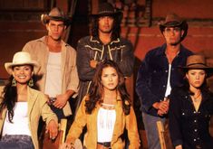 a group of people standing next to each other in cowboy hats and jeans on stage