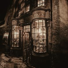 an old fashioned store front at night with its lights on and windows lit up in the dark