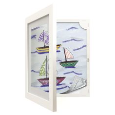 an open white frame with sailboats painted on the glass and inside it is in front of a white wall