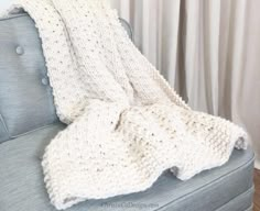 a white knitted blanket sitting on top of a blue couch