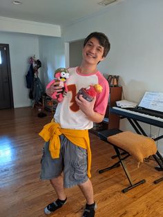 a young man standing in front of a piano holding a toy and smiling at the camera