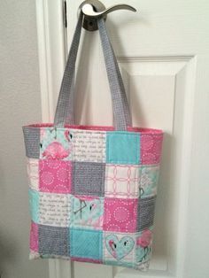 a pink and blue patchwork bag hanging from a hook on a white door handle