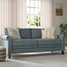 a living room scene with focus on the couch and pillows in front of the window