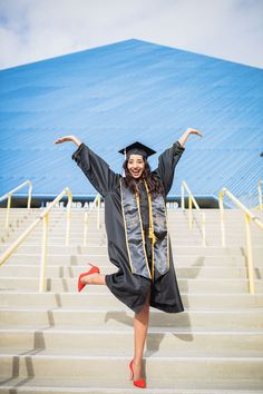 a woman in graduation gown and red high heels running down stairs with her arms outstretched