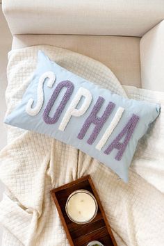 a pillow that says sophia on it next to a candle and other items