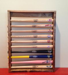 a wooden baseball bat rack with six bats in it on top of a red table