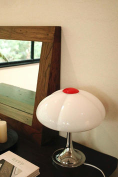 a white lamp sitting on top of a wooden table next to a mirror and candle