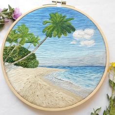 an embroidery project with palm trees on the beach and water in the ocean behind it