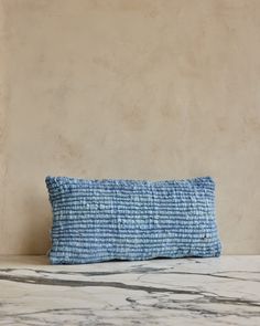 a blue and white pillow sitting on top of a marble counter next to a wall