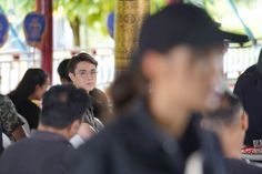 many people are sitting at tables with drinks in their hands and one person is wearing a black hat