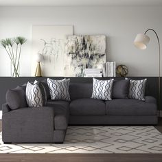 a living room with a large gray couch and pillows on the floor next to a lamp