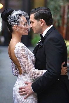 a man in a tuxedo kissing a woman wearing a veil on her head