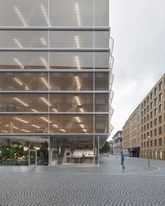 a large building with lots of windows on the side and people walking around in front