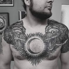 a man with tattoos on his chest and two wolfs around the moon in front of him