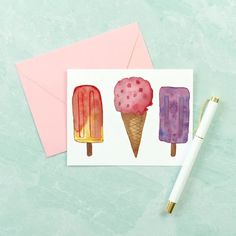 three ice creams on top of each other next to a pink envelope and pen