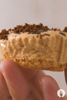 a hand holding a half eaten dessert with frosting and crumbs on it