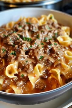 a close up of a bowl of food with meat and noodles in it on a table