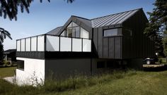 a black and white house sitting on top of a lush green field