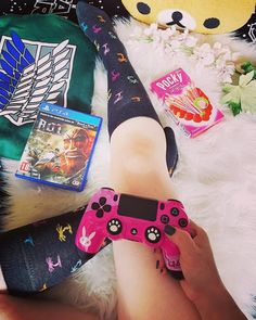 a person holding a pink game controller in their hand next to some toys and other items