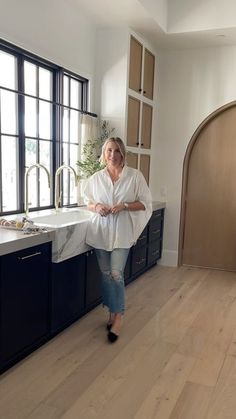 a woman standing in the middle of a kitchen