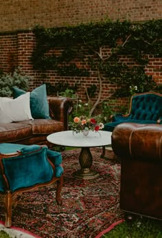 a living room with couches, chairs and a rug in front of a brick wall