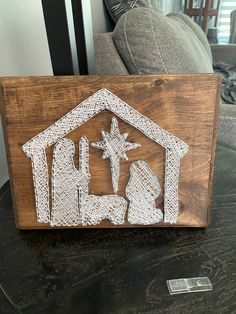 the nativity scene is made out of string and wood, on a table in front of a couch