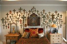 a bedroom with many crosses on the wall above the bed and dressers in front of it