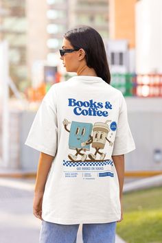 a woman is walking down the street wearing a t - shirt with books and coffee on it