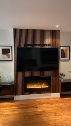 a living room with hardwood floors and a flat screen tv mounted above the fire place