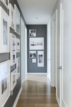 a long hallway with pictures on the wall and wooden flooring, along with white framed photos