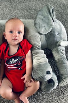 a baby sitting on the floor next to an elephant